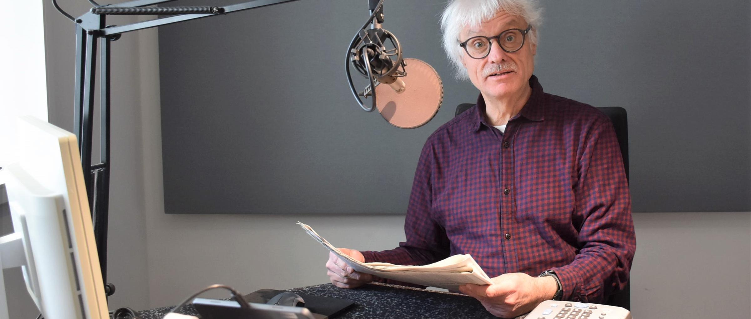 Ein Mann mit Papier in den Händen sitzt vor einem Mikrofon