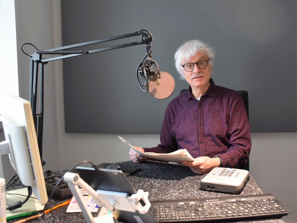 Ein Mann mit Papier in den Händen sitzt vor einem Mikrofon