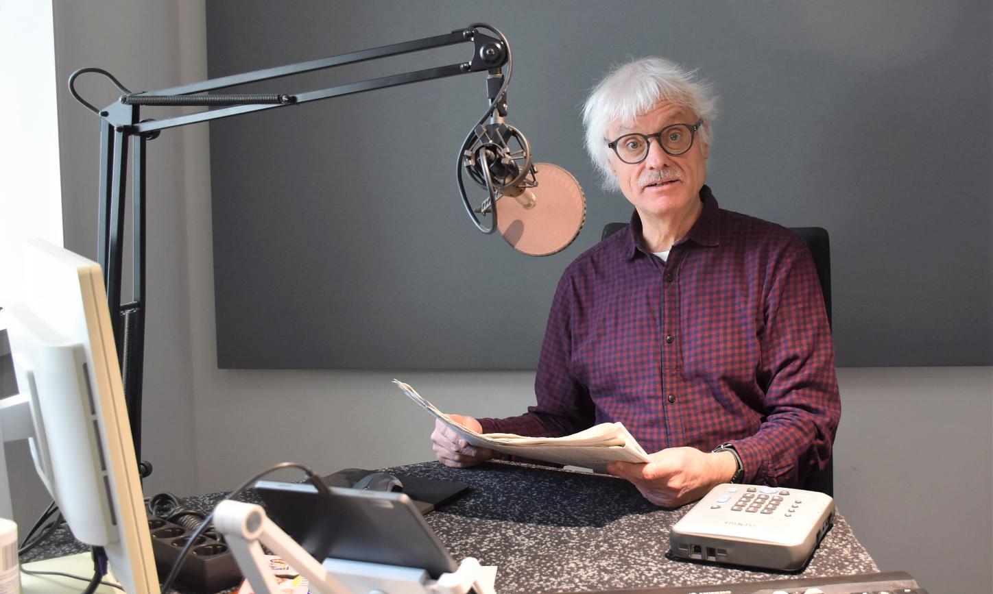 Ein Mann mit Papier in den Händen sitzt vor einem Mikrofon