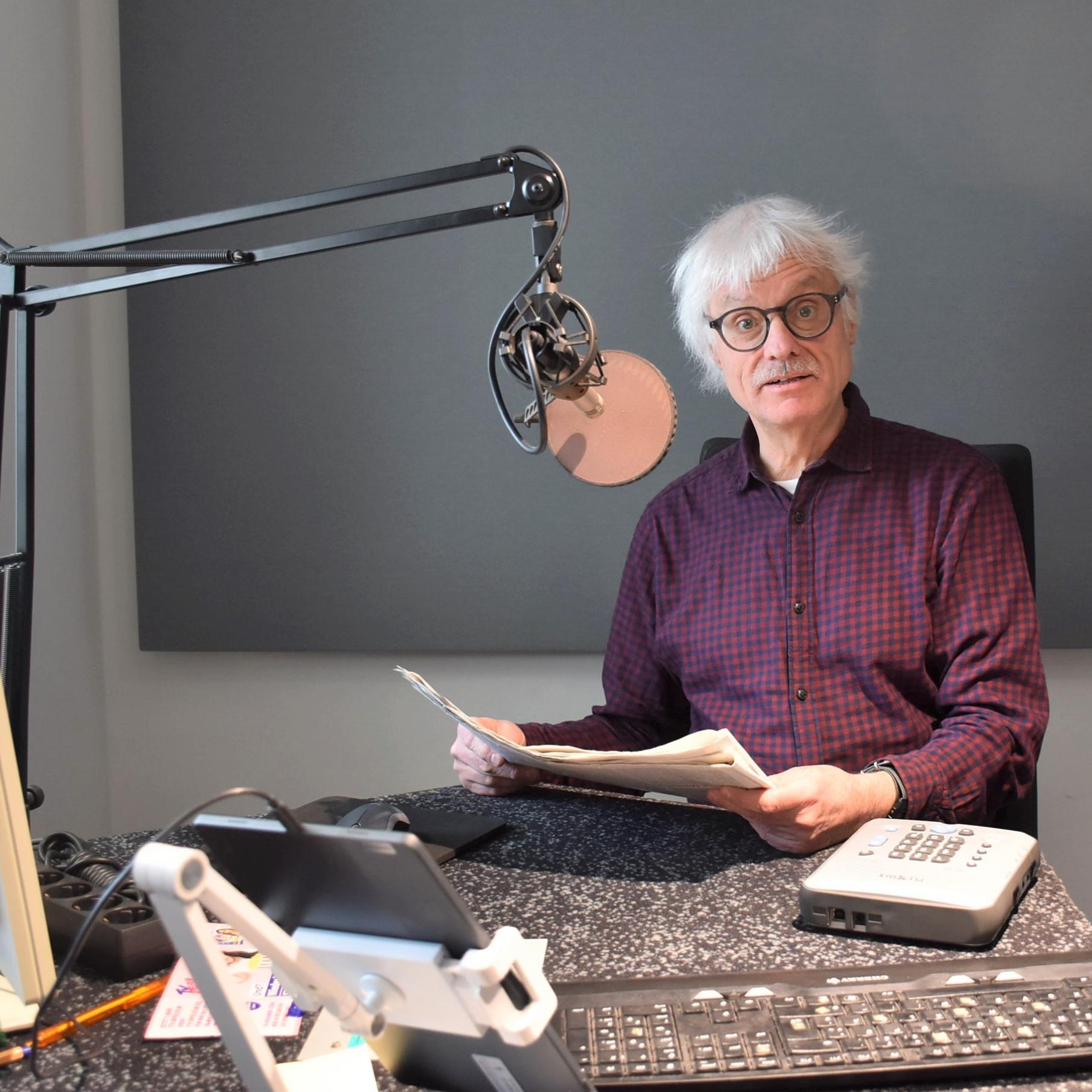 Ein Mann mit Papier in den Händen sitzt vor einem Mikrofon