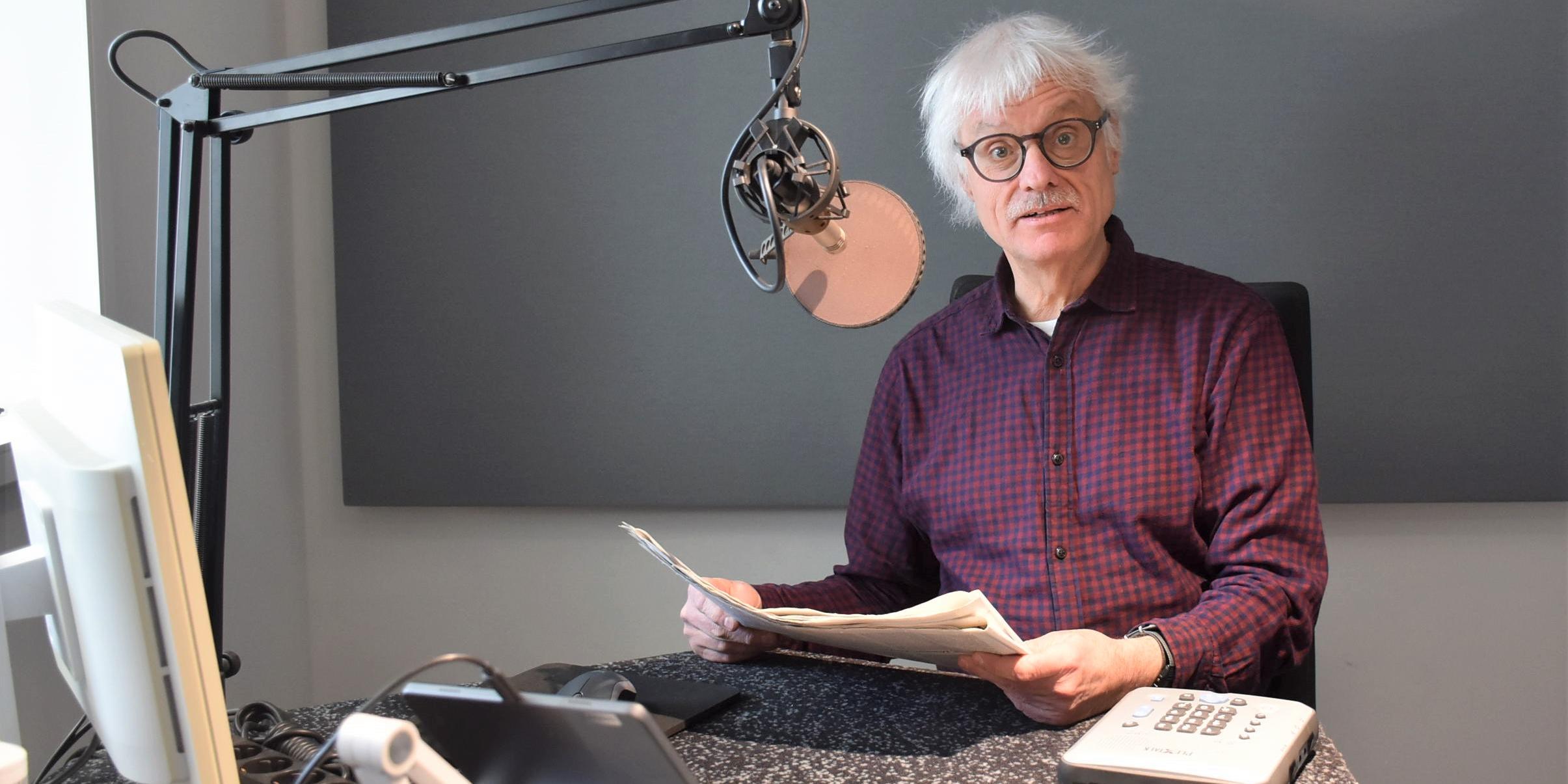 Ein Mann mit Papier in den Händen sitzt vor einem Mikrofon